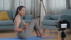 Young Asian Trainer Female In Sports Clothes Speaking To Camera And Doing Crisscross Crunch Workout While Recording Teaching Exercise At Home
