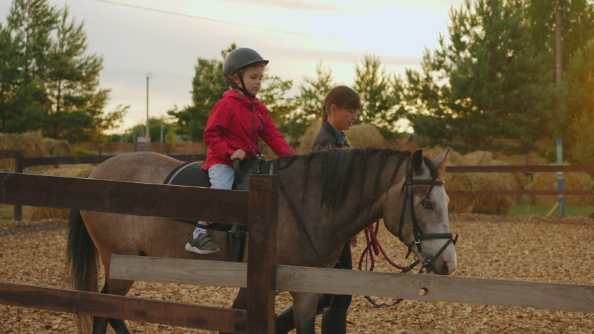 Hippotherapy and therapeutic horseback riding in pony club, little boy and female coach are practicing in paddock | Shutterstock HD Video #1094854273