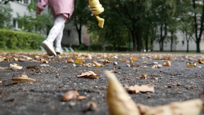 Child runs through yellow, autumn leaves and acorns.