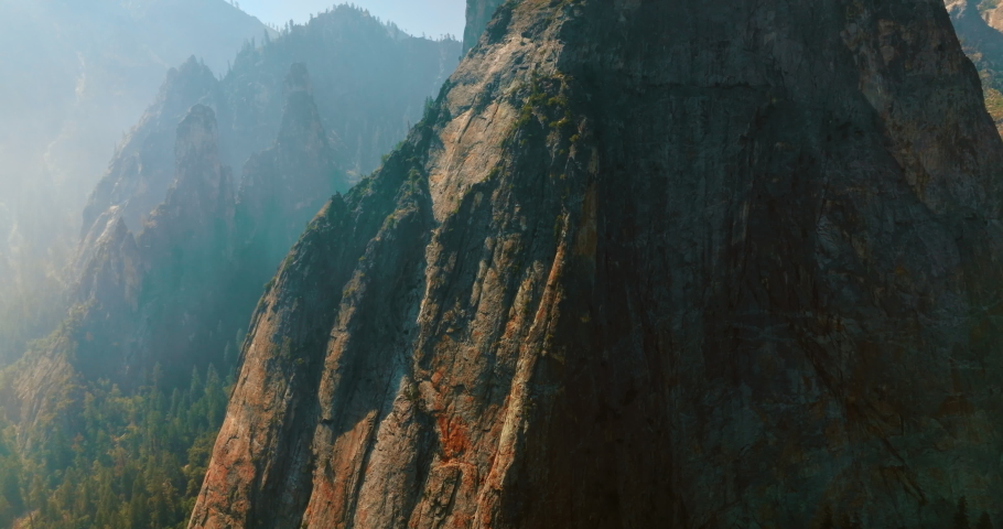 Sharp steep cliffs covered with thick white fog in Yosemite National Park, California, USA. Drone footage among the powerful rocks.