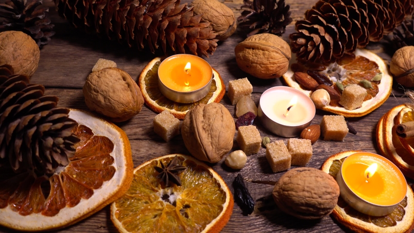 Natural composition in hygge style with candles, orange slices, fragrant spices, walnuts and pine cones on an old vintage wooden board background. - Powered by Shutterstock - Get 15% off with code: PIKWIZARD15