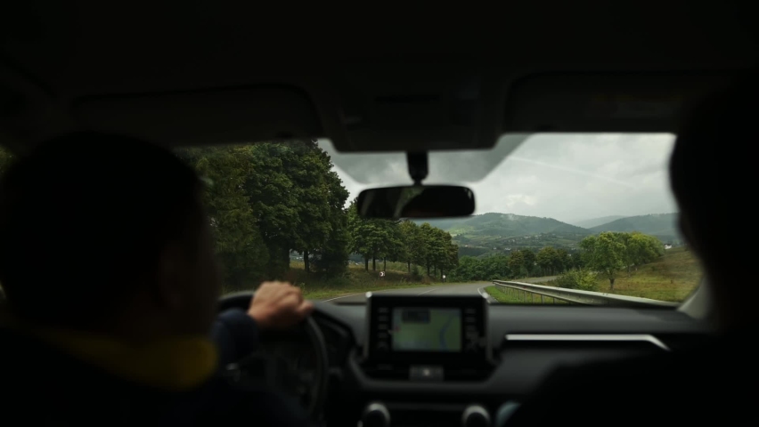 A car ride through mountain serpentines. View from the car where two men are talking, using navigation | Shutterstock HD Video #1094864071