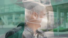 Animation of flag of nigeria waving over caucasian man wearing face mask in city street. global health precautions during covid 19 pandemic concept digitally generated video.