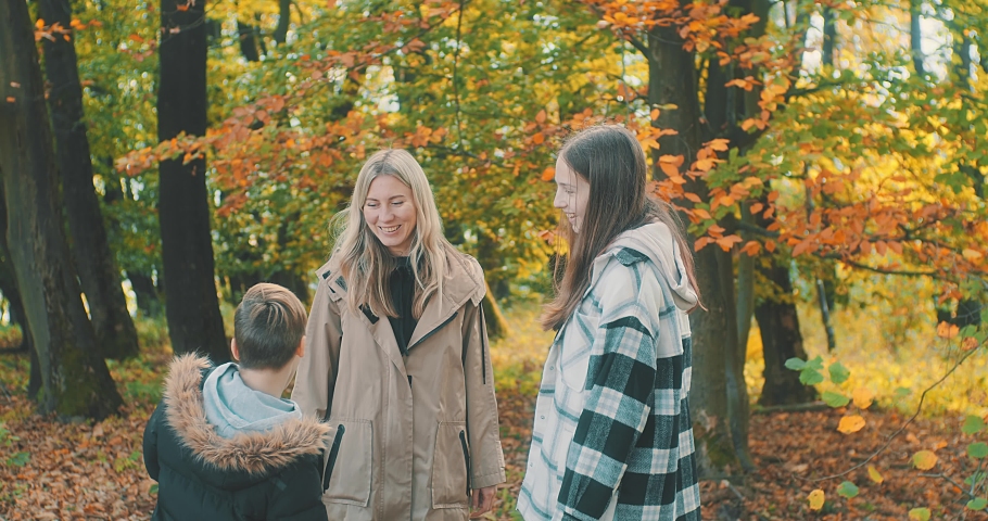 Happy family outdoors while spending his free time in autumn forest, Mother and children are happy to walk park, Parents hold the child by the hands. Enjoy time together. Natural colors. | Shutterstock HD Video #1094866467