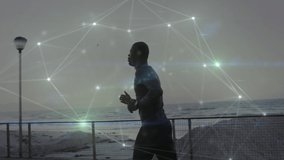 Animation of network of connections over fit african american man jogging on beach. healthy active lifestyle and global networks concept digitally generated video.