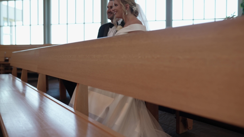 Bride and groom sitting on a wooden pew in a modern church. Crane shot | Shutterstock HD Video #1094872841