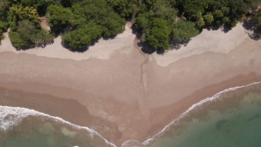 Static aerial view of diagonal waves crashing onto a beautiful empty beach in a peaceful location on Costa Rica
