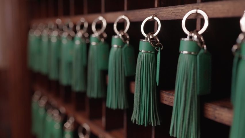 Hotel key rack made of mahogany with green tassels attached to each key. Royalty-Free Stock Footage #1094873223