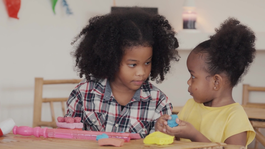 Two little african american  kids learning playing together sculpting plasticine create different shapes. Activity at home, pastime craft and hobby concept.