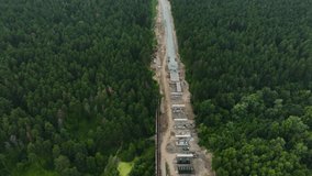 Construction of a road bridge in a green forest in summer. Aerial view
