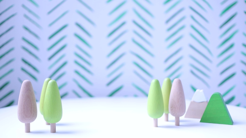 Landscape of trees and wooden mountains in which a toy lion appears