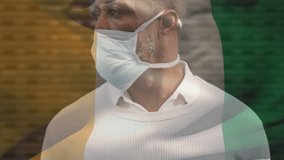 Animation of flag of ivory coast waving over african american man wearing face mask in city street. global health precautions during covid 19 pandemic concept digitally generated video.