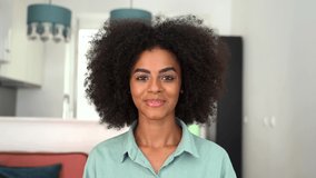 Multiracial brunette female during video call, involved virtual meeting, waving at the camera, saying hello. Job hunting concept. Webcam view of african-american young woman