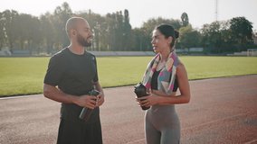 Friends couple chats holding shakers after training on stadium. Young African American man and biracial woman say goodbye with fist bumps smiling slow motion - Powered by Shutterstock - Get 15% off with code: PIKWIZARD15