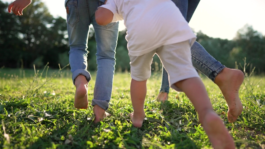 Outdoor lifestyle.Children have rest and have fun in park in fresh air. children run in park with bare feet on green grass. close-up of group of children running on green grass in summer.