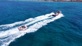 Aerial drone video of extreme inflatable towable tube cruising in high speed attached on powerboat , water-sport