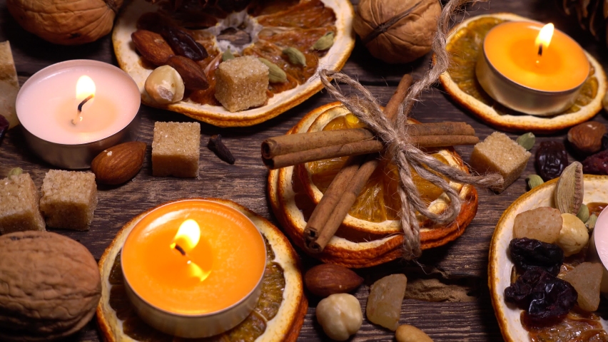 Natural composition in hygge style with candles, orange slices, fragrant spices, walnuts and pine cones on an old vintage wooden board background. - Powered by Shutterstock - Get 15% off with code: PIKWIZARD15