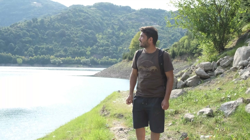 Backpaker Exploring Nature, traveler on the forest lake scenery, walking by the lake, hiking activity in the forest for relaxation