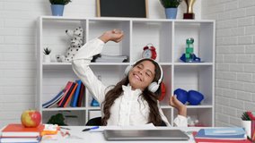 happy teen girl in headphones stretching after at school online lesson with computer, back to school
