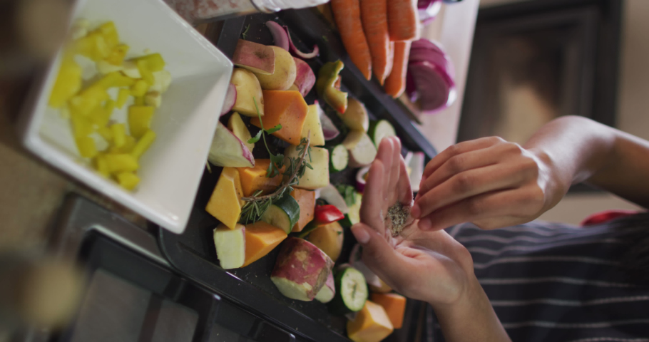 Vertical video of midsection of biracial woman seasoning vegetables. Friendship, spending quality time together at home. | Shutterstock HD Video #1094911789