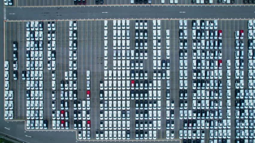Drones flying above factory parking lot, new cars unsold. import and export industry. automotive industry. 4K
