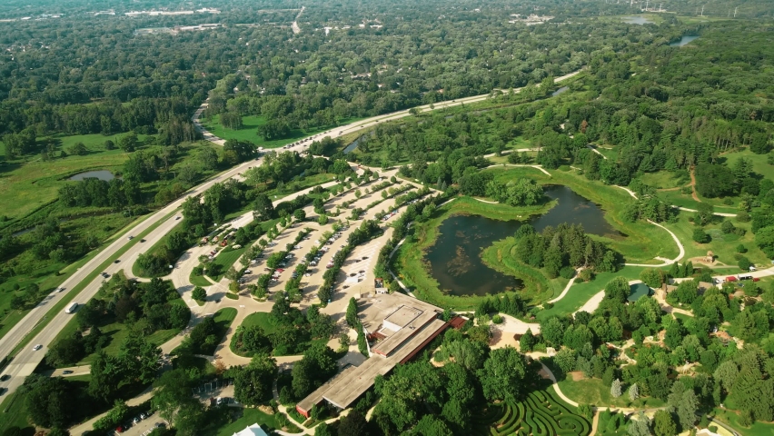 An aerial shot of Morton Arboretum park along with the greenish garden and an asphalt road also seen outside the park. A beautiful eye soothing view has been captured by drone