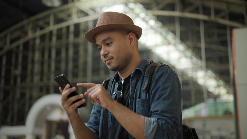 Traveler young asian man talking on cell phone at terminal train station. Happy tourist travel by train. Male Backpacker arrival at platform railway. Freedom trip on vacation time holiday weekend. Royalty-Free Stock Footage #1094916849
