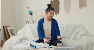 Beautiful young woman talks to her friend through the video camera on phone shows new apartment, the colors of the walls she has chosen for the apartment, the joy excitement of the upcoming move.