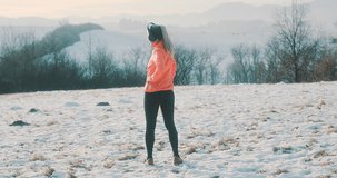 Run Woman, headphone girl runner on the snow in winter sunny day. Female in pink sportswear jacket fitness training outdoors, healthy lifestyle and vitamins, 4K slow motion video