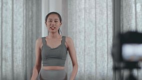 Young Asian Trainer Female In Sports Clothes Speaking To Camera And Doing Cardio High Knees While Recording Teaching Exercise At Home
