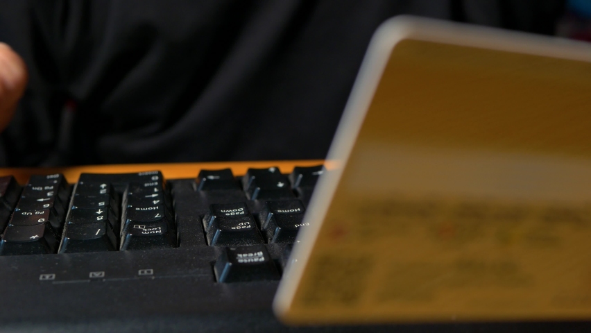 Paying for a purchase with a credit card online. Credit card in a man's hand. A man enters a credit card number using a computer keyboard. Close-up, selective  | Shutterstock HD Video #1094925605