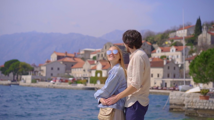 A young couple is hugging standing at the embankment of the city of Perast, a beautiful coastal town in the Boka-Kotorska bay. Travel to Montenegro concept. Slowmotion video | Shutterstock HD Video #1094935861