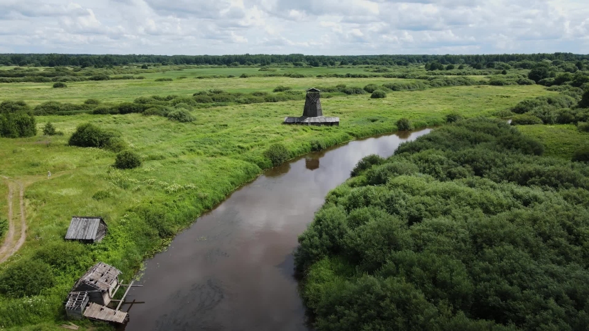 Aerial view an old wooden mill stands on an island in a green field by the river in summer | Shutterstock HD Video #1094935973