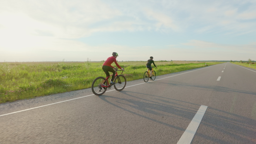 Caucasian racing bicyclists riding during intensive training along paved road. Two men in activewear and helmets preparing for cycling international competitions. | Shutterstock HD Video #1094937101