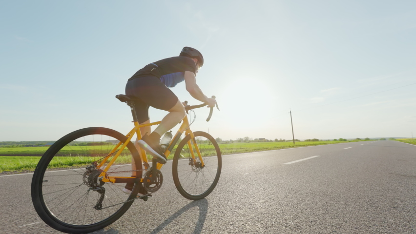 Rear view of professional cyclist in black sport outfit and safety helmet training on road bike along highway. Concept motivation, endurance and people. | Shutterstock HD Video #1094937115
