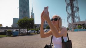 photographer girl holds in her hands mobile phone photographing on smartphone modern city, tourist shooting on camera against background of Gorord architecture, internet online concept