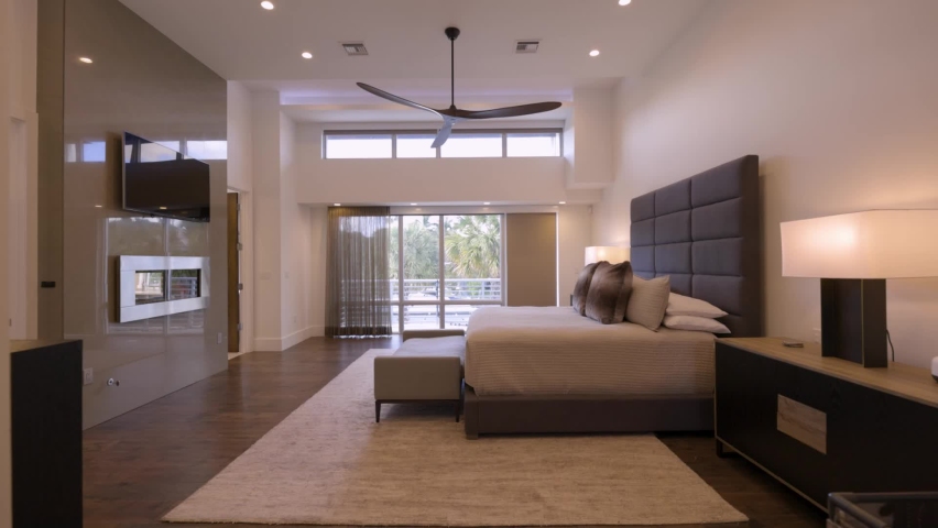zoom in of luxury room with window with palm trees in the background, tv and fireplace
