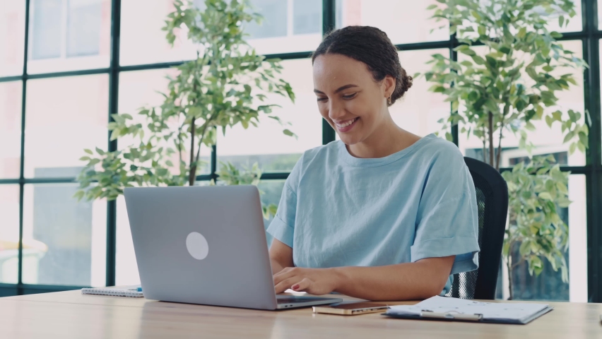 Video in motion of a lovely businesswoman. Positive successful latino or brazilian curly young woman, company top manager, entrepreneur, sits at a desk in a modern office, typing on a keyboard, smiles | Shutterstock HD Video #1094955169