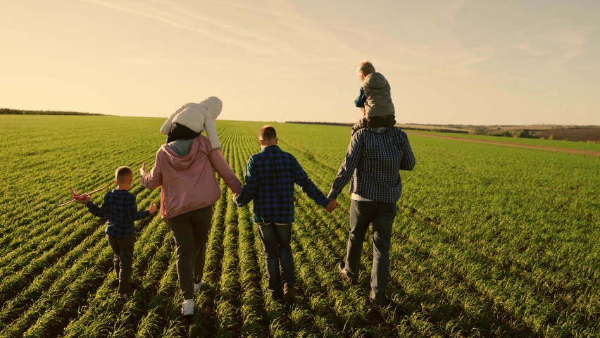 Family, mom, kids, dad walk on green grass, holding hands, dreams. Happy family of farmers with children walking in green field of wheat sprouts. Dad, mom, children, son walk in countryside under sun | Shutterstock HD Video #1094955353