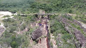 aerial drone shot of hard rocky and brown river in the middle of dry hills. old bridge over the river on rocky hills. 4K videos.
