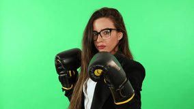 Businesswoman woman with glasses white shirt and black business suit wearing boxing gloves and punching stress. Green screen for chroma key in background - Powered by Shutterstock - Get 15% off with code: PIKWIZARD15