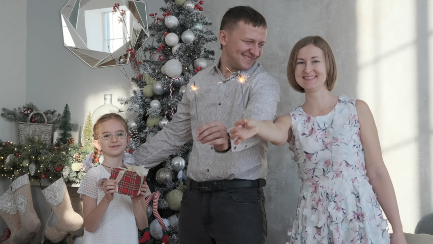 Happy family of three holding sparklers in hands while celebrating Christmas eve or New Years day at home, slow motion | Shutterstock HD Video #1094960337