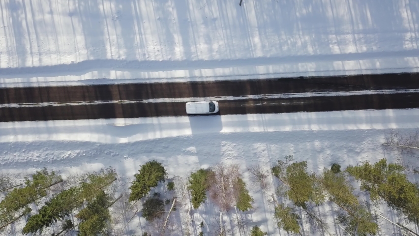 Winter icy road conditions in Finnish Lapland. Drone flying slowly left to right and camera is straight down. Black car and white van driving in same way over image area.