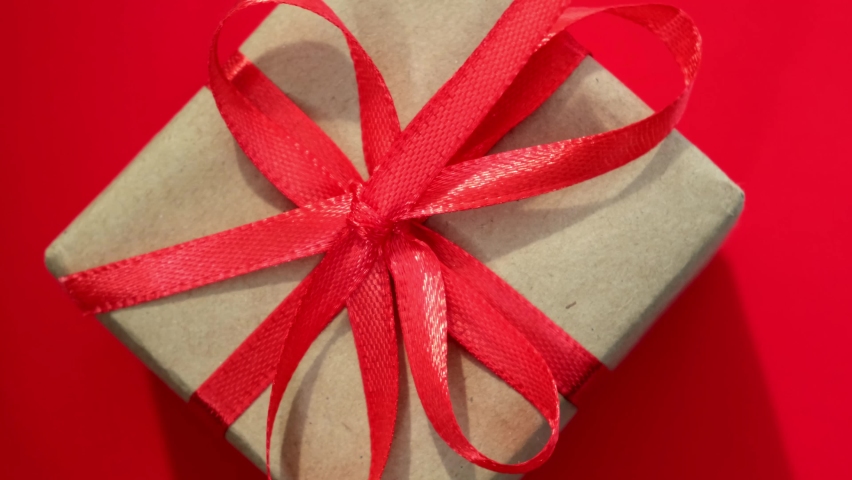 Close up rotation of gift box on red background. Minimalist concept for Christmas, New Year, Valentines day, Mothers day, Women day, wedding or birthday celebration. Greeting card | Shutterstock HD Video #1094962319