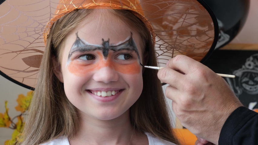 Happy family preparing for Halloween. Dad draws aqua grim on child girl face for holiday party. Father and daughter getting ready for halloween making makeup. Close up | Shutterstock HD Video #1094962337