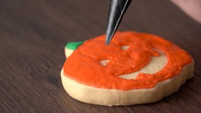 Close up of decorating cute Halloween pumpkin gingerbread cookies with frosting icing cream topping bag, making sugar cookies. - Powered by Shutterstock - Get 15% off with code: PIKWIZARD15