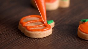 Close up of decorating cute Halloween pumpkin gingerbread cookies with frosting icing cream topping bag, making sugar cookies. - Powered by Shutterstock - Get 15% off with code: PIKWIZARD15