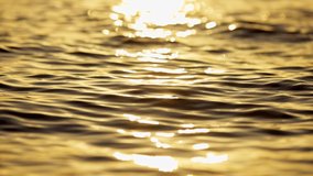 Reflection of golden sunlight over the sea or ocean. Slow motion shot of sea water surface at sunset. UHD 4K - Powered by Shutterstock - Get 15% off with code: PIKWIZARD15