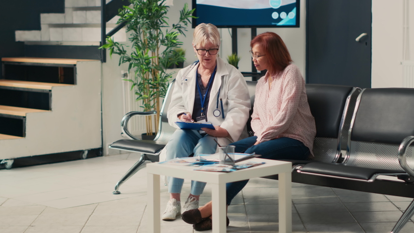 Asian patient with physical health condition doing consultation in waiting area lobby, talking about disability. Woman wheelchair user with impairment receiving healthcare support. | Shutterstock HD Video #1094968425