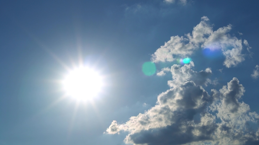 Bright Noon Sun on Blue Sky with Puffy Clouds Low Angle View TimeLapse. Sun Shining on Summer Sunlight Sunbeam Sun Ray Flares with White Cumulus Cloud at Midday Sunshine Day. Beautiful Background. Royalty-Free Stock Footage #1094968795